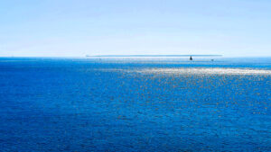 Il mare blu e il cielo azzurro, sul mare il riflesso bianco del sole